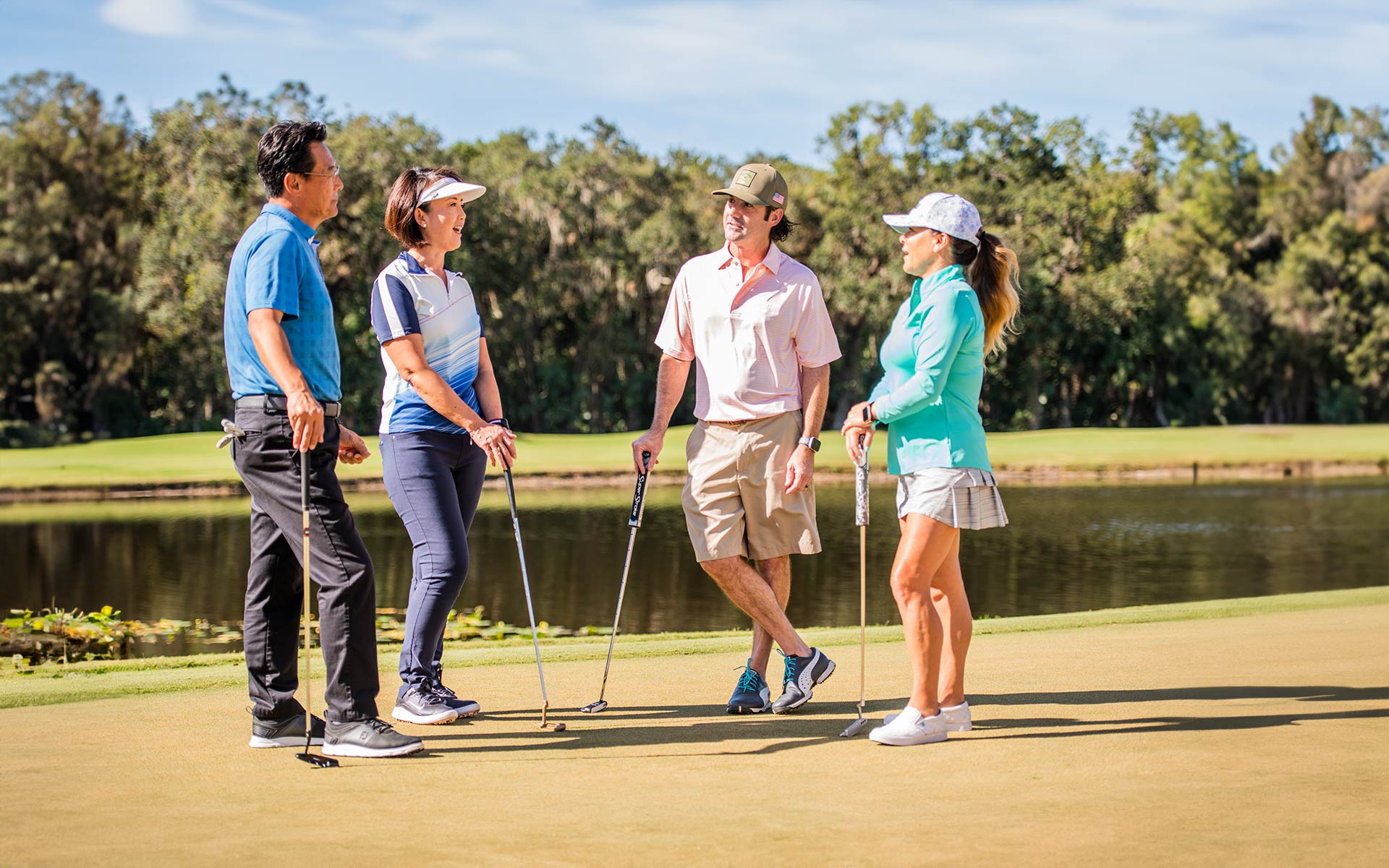 Adult golfers conversing on the green of an Invited Club golf course..